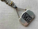 closeup of antique sterling silver compact pendant with black enamel on chain mix