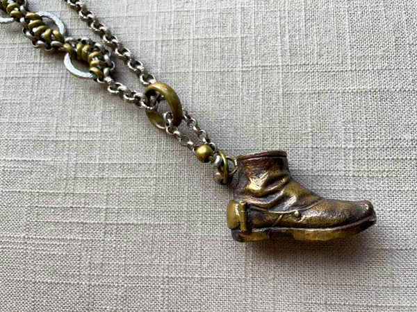 closeup of antique bronze boot match safe on chain mix