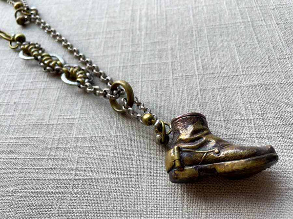 closeup of antique bronze boot match safe on chain mix