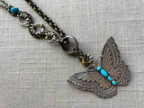 closeup of modern sterling silver butterfly pendant with turquoise on chain mix