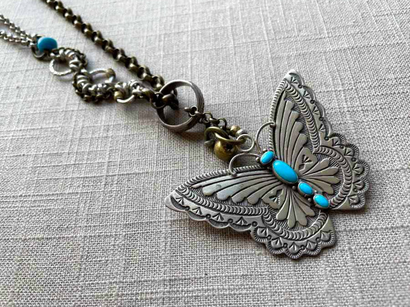 closeup of modern sterling silver butterfly pendant with turquoise on chain mix