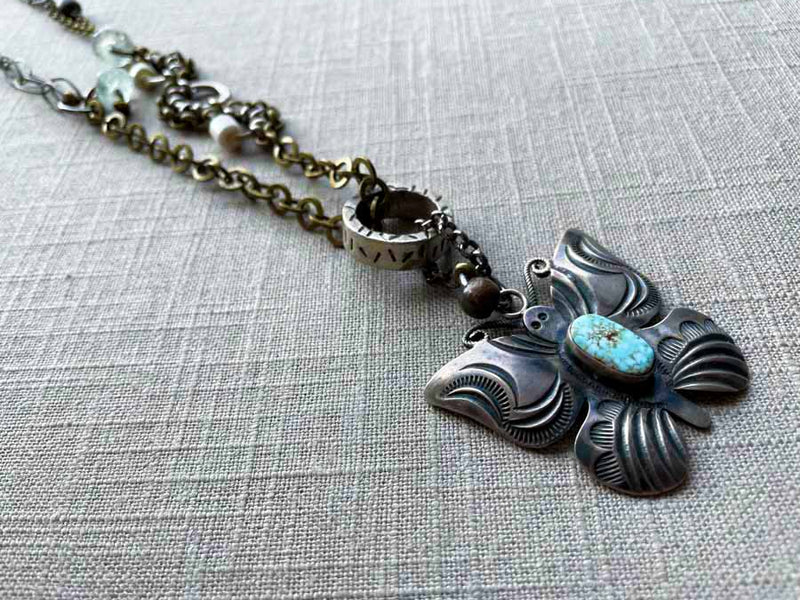 closeup of modern sterling silver butterfly pendant with turquoise on chain mix