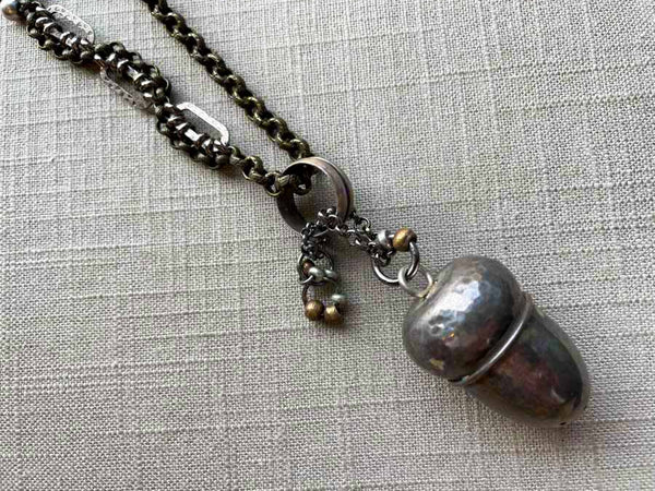 closeup of antique sterling silver acorn pepper shaker pendant on chain mix