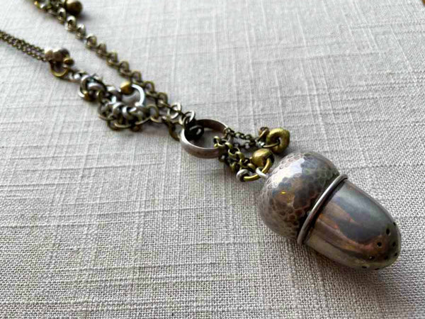 closeup of antique sterling silver acorn pepper shaker pendant on chain mix