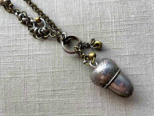 closeup of antique sterling silver acorn pepper shaker pendant on chain mix