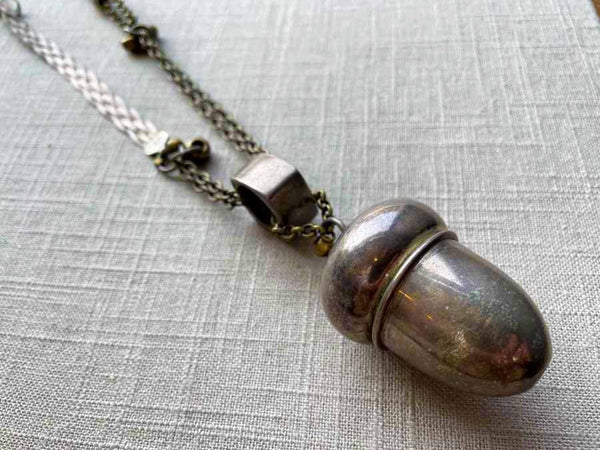 closeup of antique sterling silver acorn salt shaker pendant on chain mix