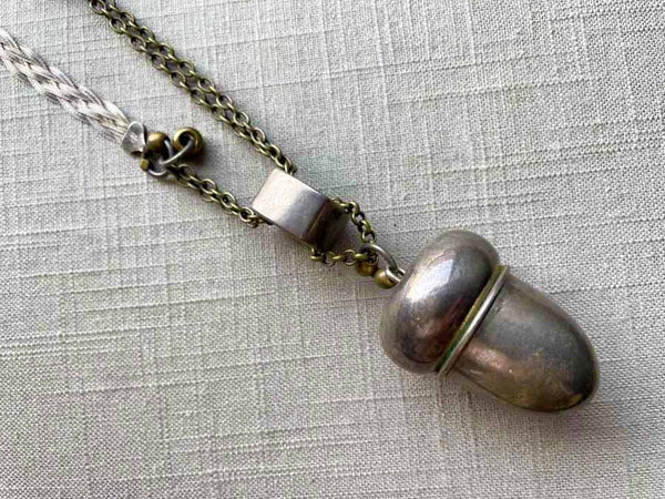 closeup of antique sterling silver acorn salt shaker pendant on chain mix