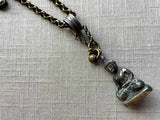 closeup of antique bronze buddha pendant on chain mix