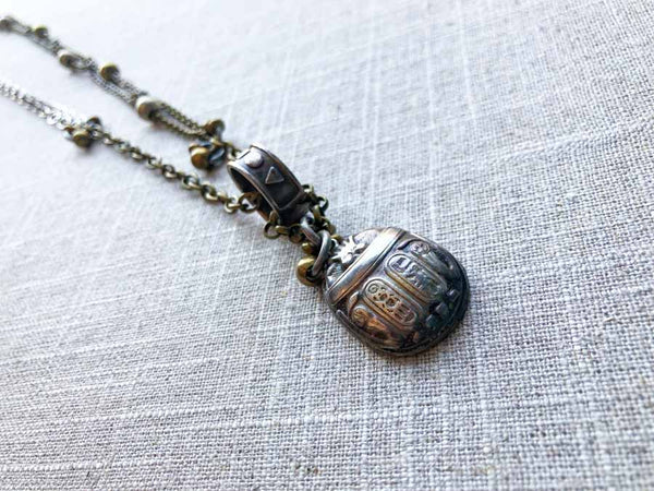 closeup of antique sterling silver scarab pendant on chain mix